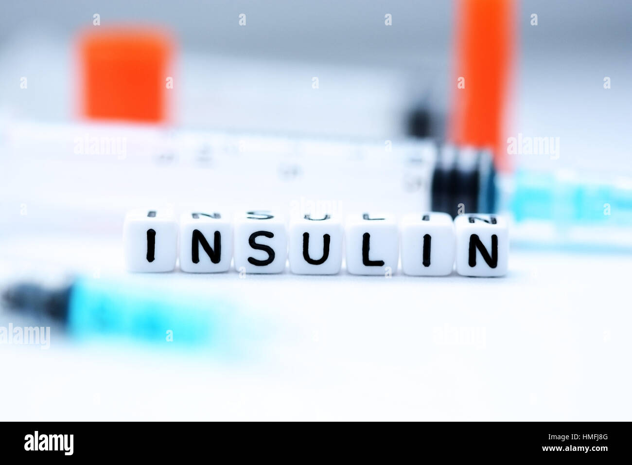 Das Wort Insulin mit Kunststoff Buchstaben perlen neben einer Spritze geschrieben Stockfoto