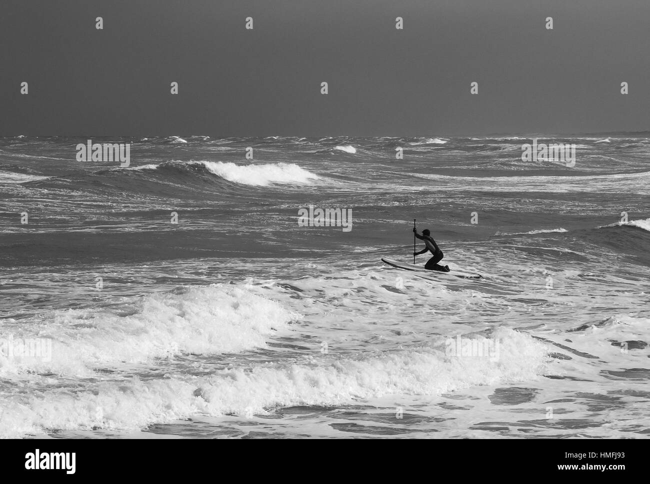 Surfer-Paddel, gegen die Wellen in der stürmischen See. Vintage schwarz / weiß Stockfoto