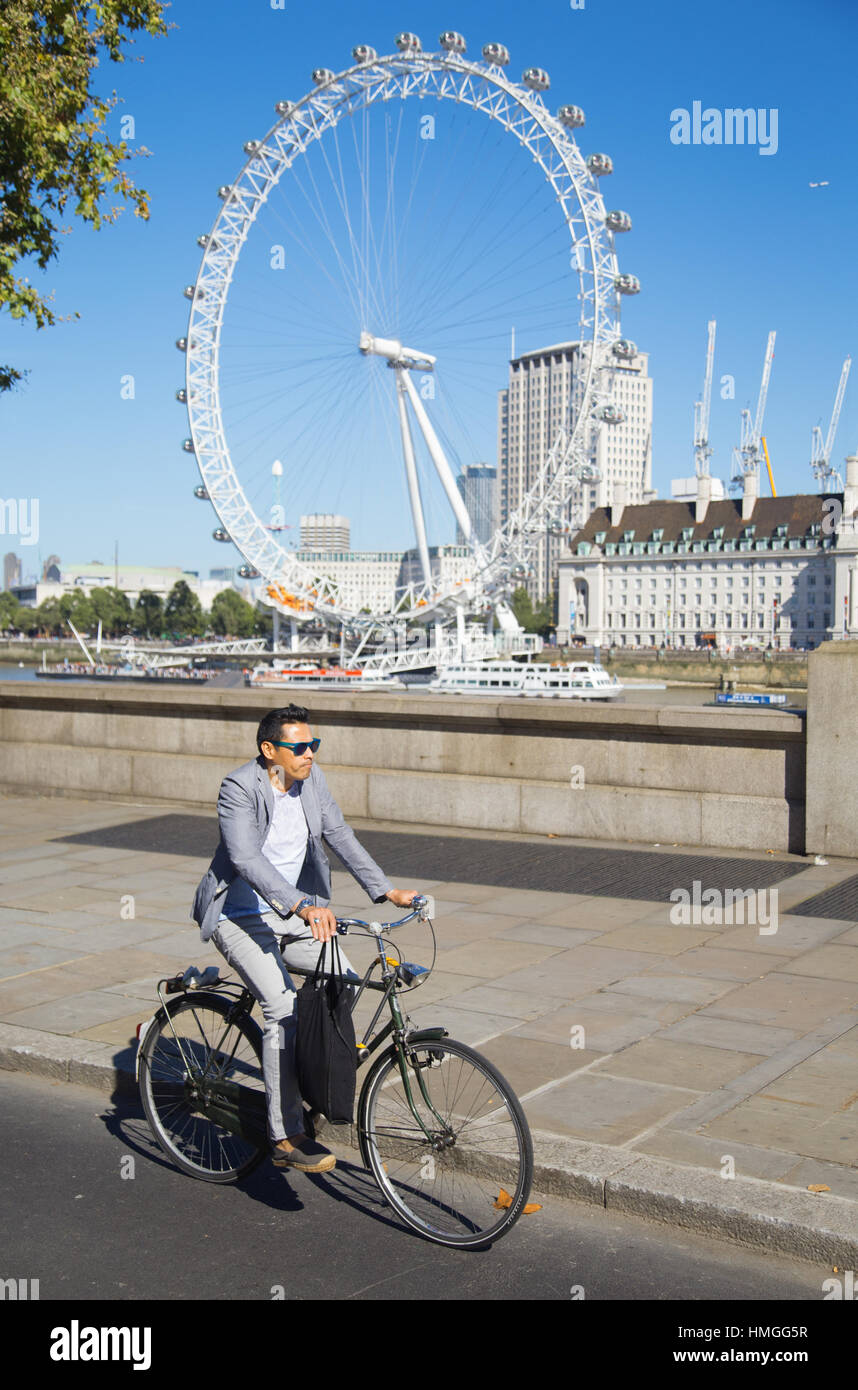 stilvoll gekleidet männliche Radsportler auf Ost-West-Zyklus Superhighway mit London Eye im Hintergrund an einem sonnigen Sommertag im Zentrum von London Stockfoto