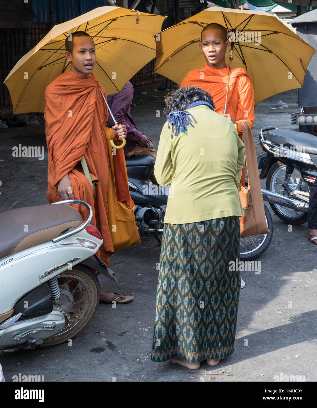 Buddhistische Mönche singen mit einem Almosen Spender auf dem russischen Markt, Phnom Penh, Kambodscha Stockfoto