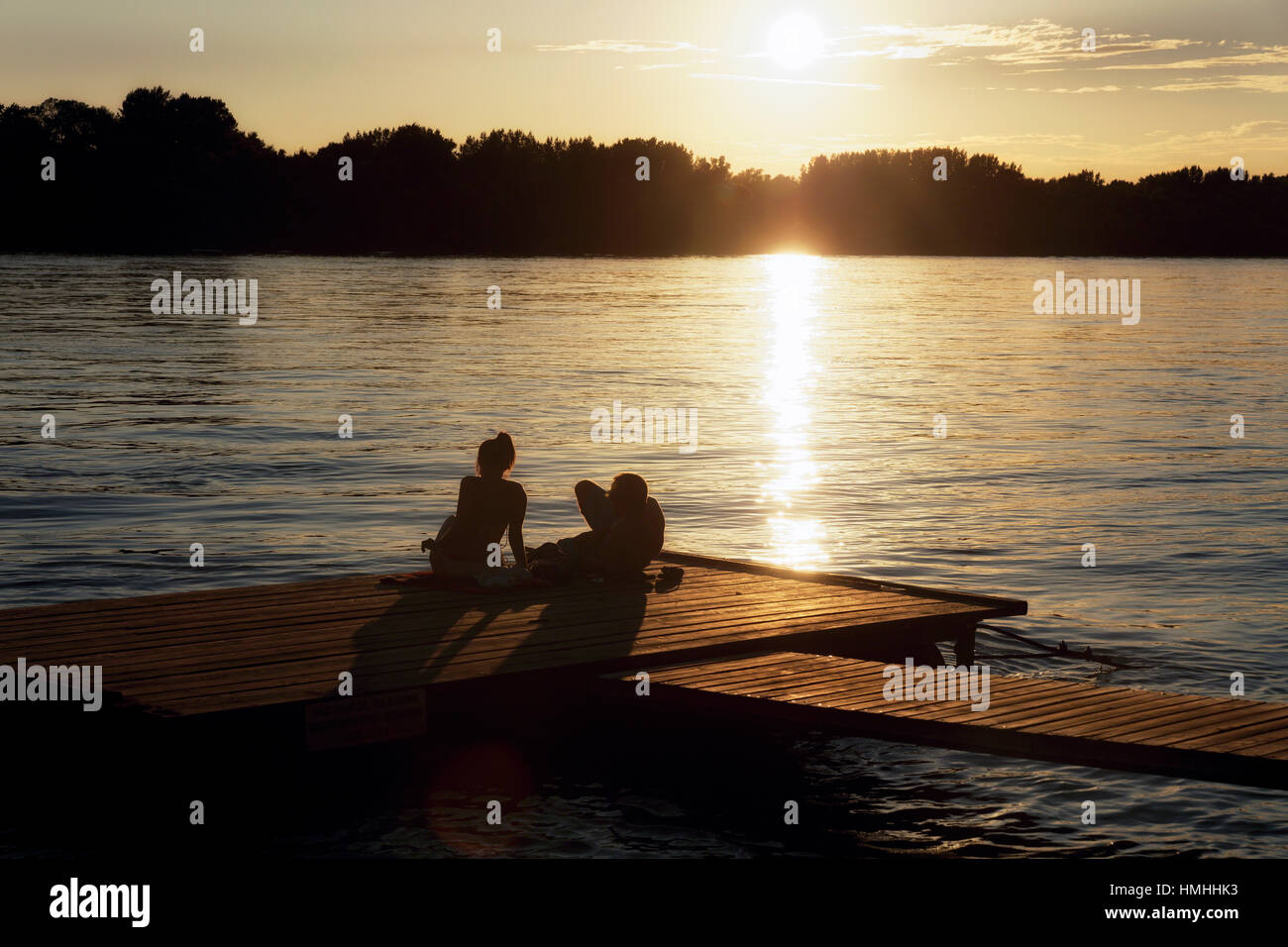 Younmg paar Entspannung auf einem Steg an der Donau bei Sonnenuntergang, Vac, Komitat Pest, Ungarn Stockfoto