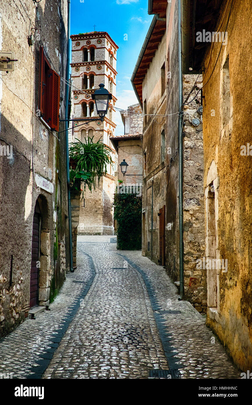 Schmale Straße mit Kopfsteinpflaster in einer mittelalterlichen Stadt führt zu einem Glockenturm, Sermoneta, Latium, Italien Stockfoto