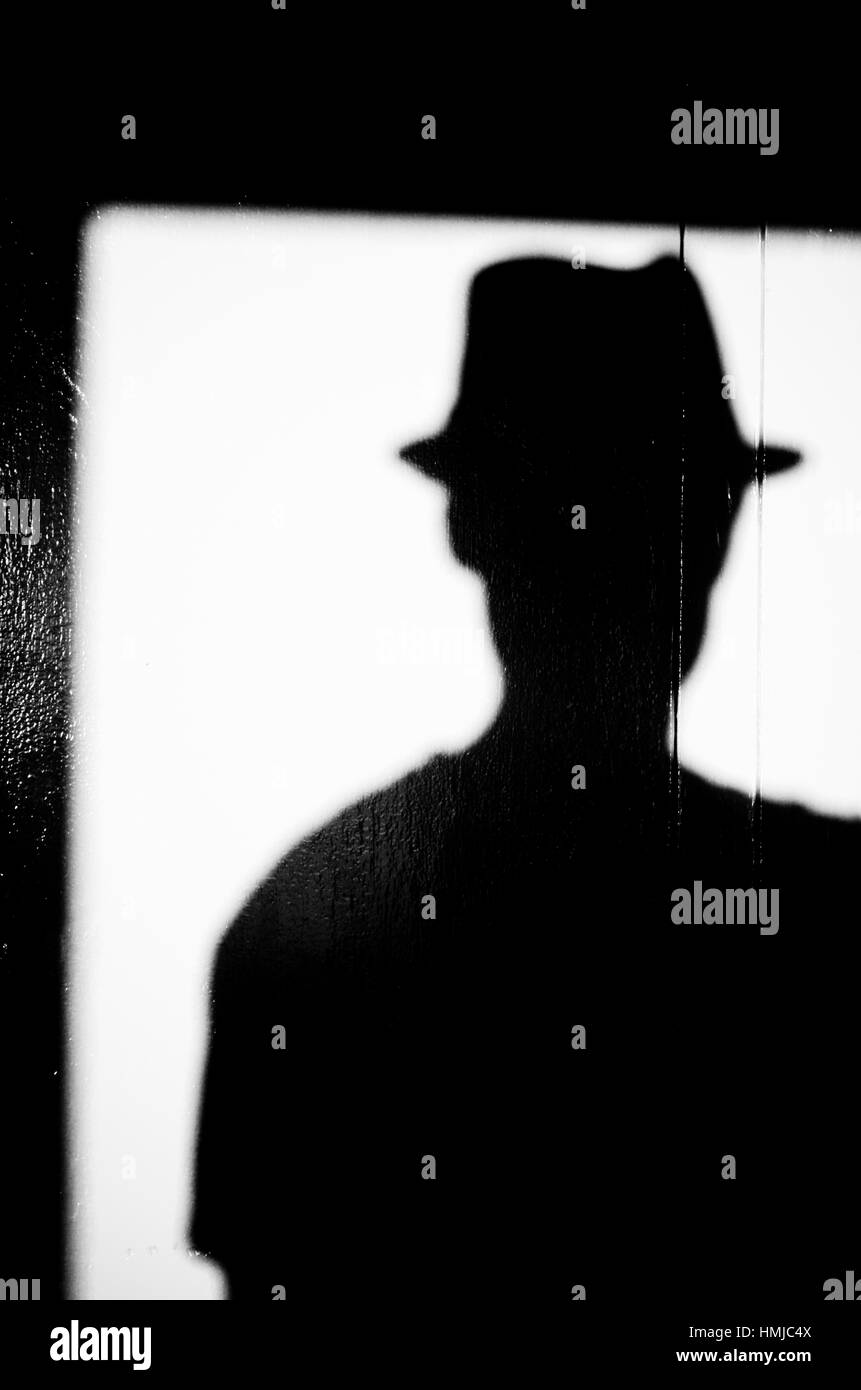 Schatten eines Mannes mit einem Hut auf einer weißen Wand. Stockfoto