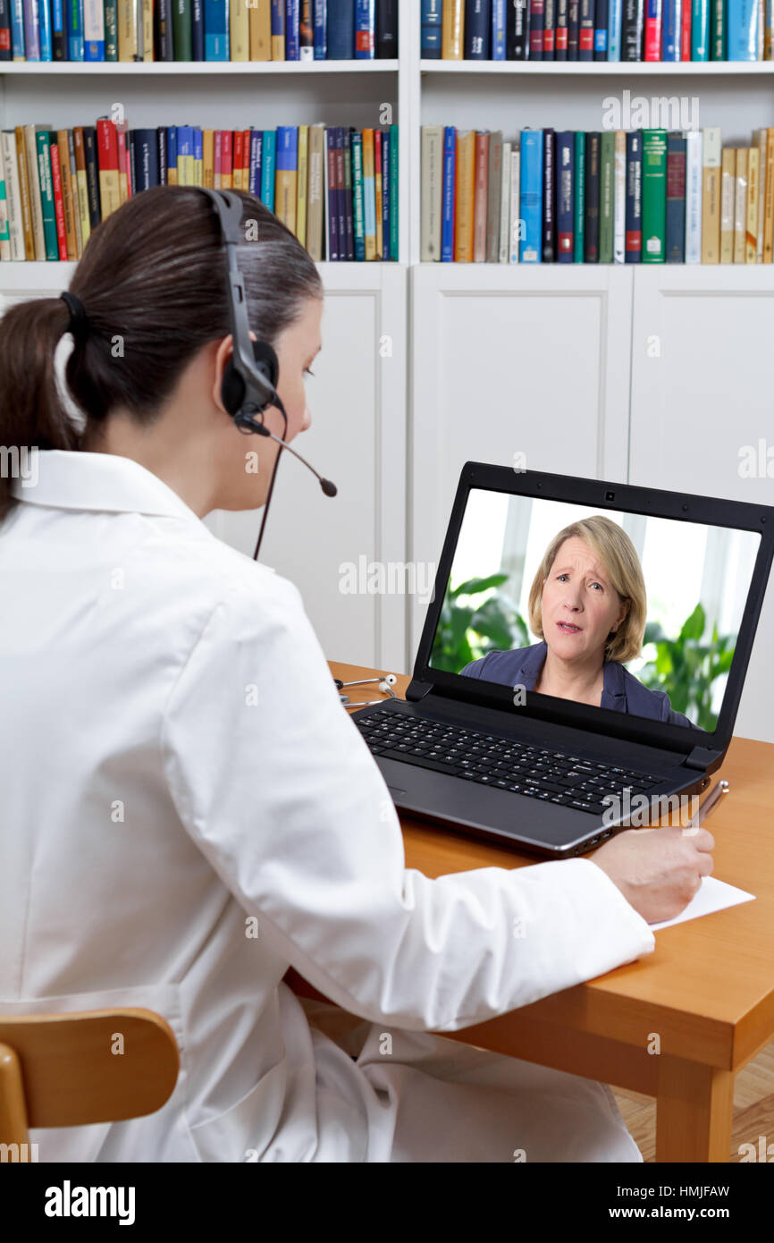 Arzt in ein Schmerz-Management-Center in ihrem Büro mit Kopfhörer und Laptop, anhören von Patienten im Todeskampf mit starken Rückenschmerzen, Telemedizin-Konzept Stockfoto