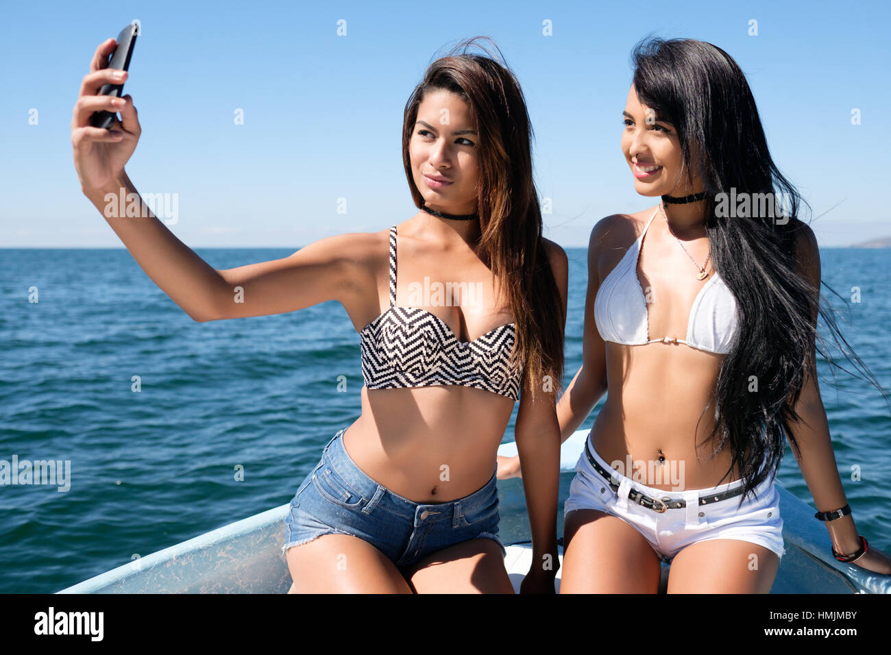 Zwei sehr attraktiven jungen hispanischen Frauen fotografieren Handy Selfie auf einem Boot Stockfoto