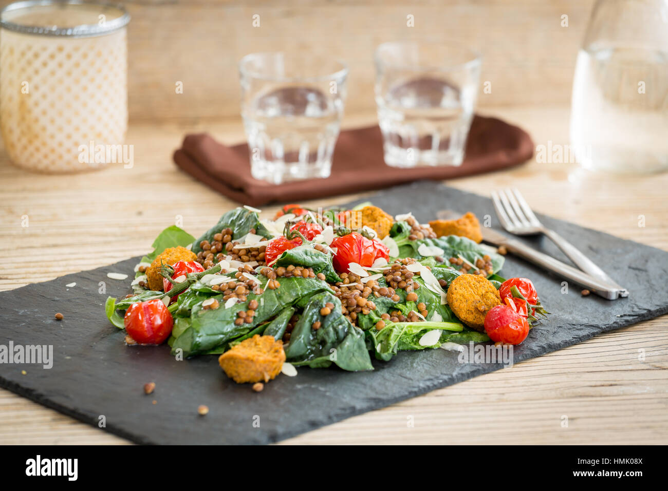 Salat mit Falafel, Linsen und gebackene Tomaten auf Steinplatte serviert Stockfoto