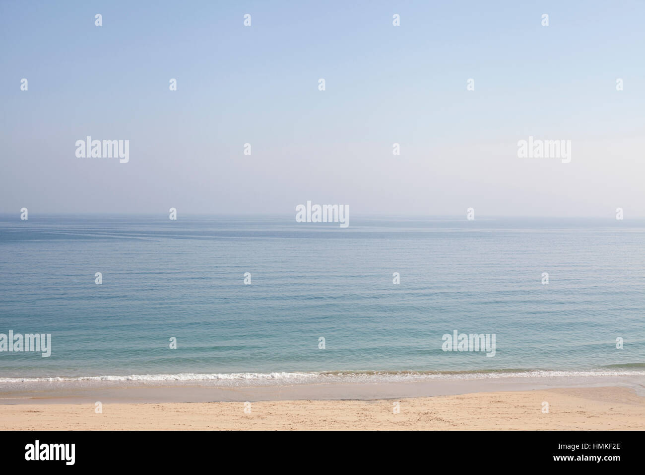 Ruhige See und blauer Himmel mit kleinen Wellen brechen sich am Sandstrand Stockfoto