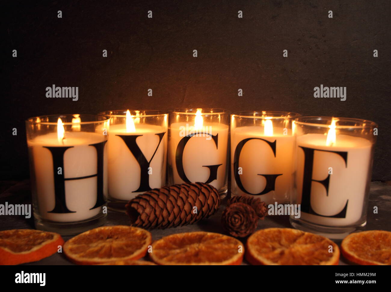 Saisonale Dekorationen und das warme Licht der Kerzen zeigen "hygge", das dänische Konzept der Gemütlichkeit und Zufriedenheit im Leben. Schiefer Hintergrund für Kopieren. Stockfoto
