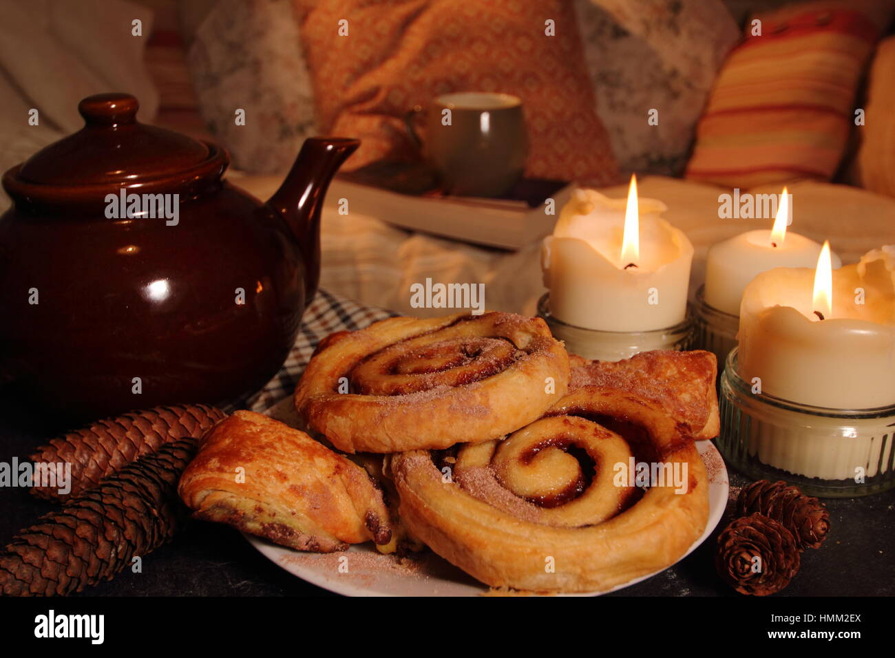 Gemütliches Kerzenlicht Wohnzimmer mit Gebäck, Tee, werfen und ein gutes Buch, in einem englischen Haus inspiriert von Hygge; eine dänische Konzept des einfachen Glücks Stockfoto