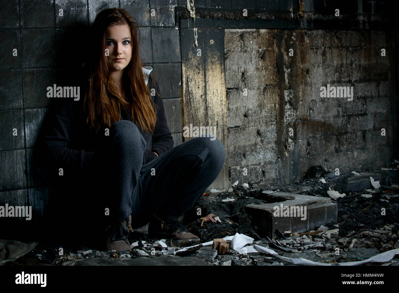 Portret eines jungen Mädchens in einem Haus zu sitzen, was durch einen Brand zerstört wird Stockfoto