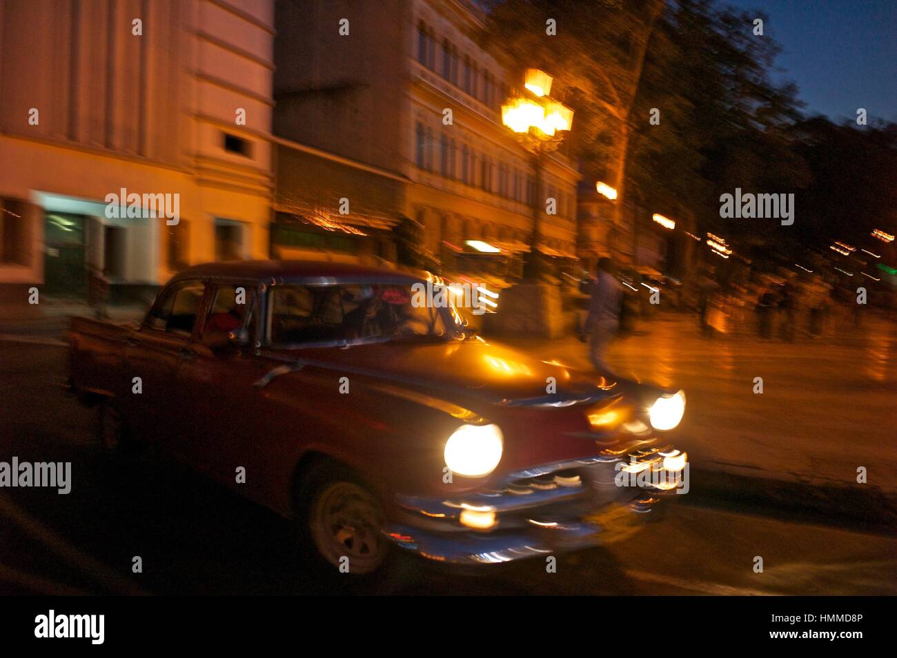 Eine alte amerikanische Auto beschleunigt in der Nacht vorbei an den Gebäuden des El Paseo del Prado in Alt-Havanna. Stockfoto