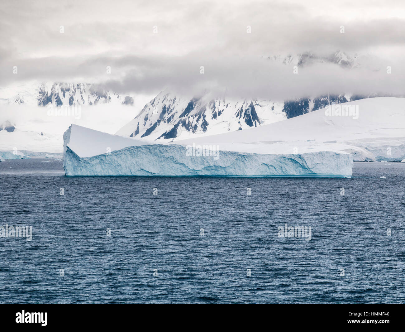Niedrige Wolken und Eisberge, die rund um die bergige Küste von Anvers Island, Neumayer-Kanal, Antarktis Stockfoto