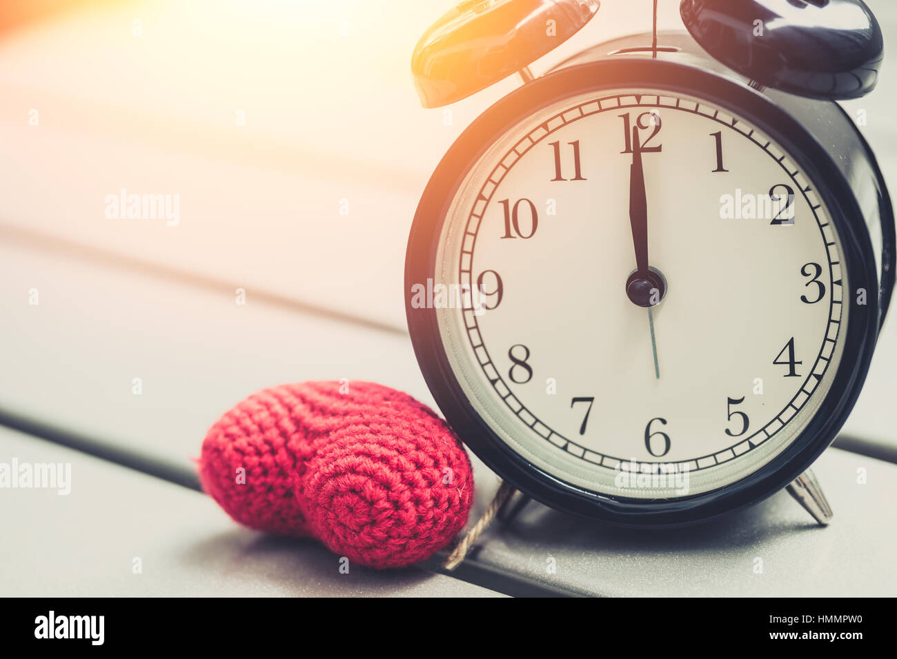 12:00 von Retro-Vintage Uhr mit roten Herzen und Sonne Licht am Morgen, Zeit oder Speicherzeiten zu lieben. Stockfoto