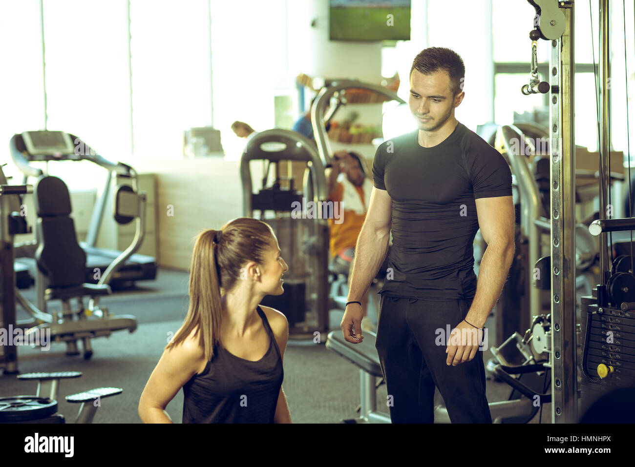 Junge männliche persönlichen Fitness-Trainer spricht mit seinen weiblichen Kunden und geben ihre Ratschläge für die Motivation. Stockfoto