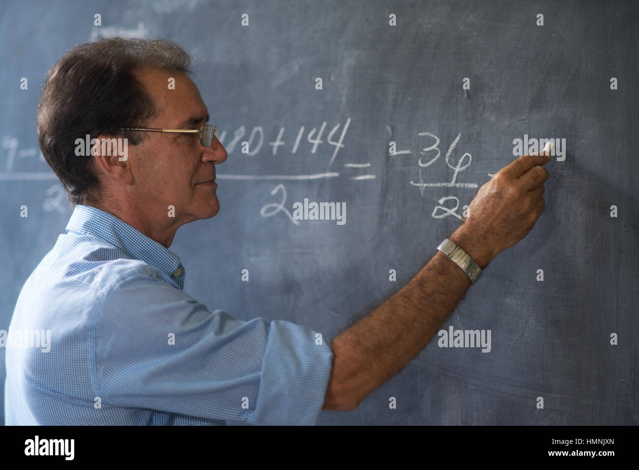 Menschen und Bildung. Lehrer schreiben auf mathematischen Gleichung auf Tafel während der Lektion. Stockfoto