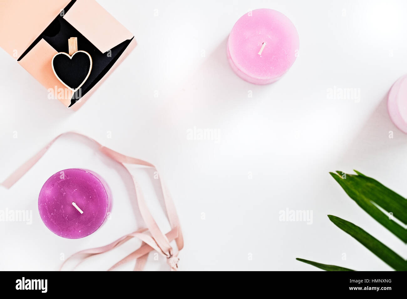 Rosa Ombre duftende Kerzen und grüne Blätter auf weiß. Frau, Deko-Ideen. Beauty Blogger flach legen Konzept. Exemplar Stockfoto