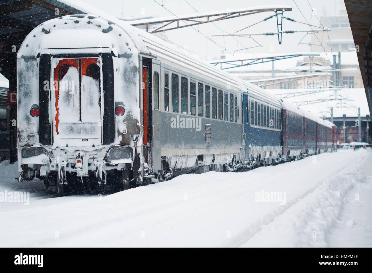 Rückansicht des Rückens ein Personenzug mit Blizzard Schnee hielten im Bahnhof, Winter mal bedeckt Stockfoto