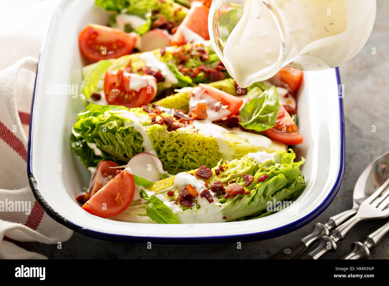 Keil-Salat mit Baby-Salat, Kirschtomaten, Speck und ranch Dressing Gießen über Stockfoto