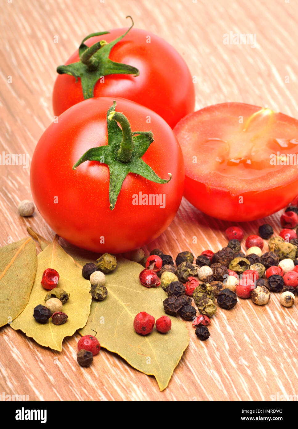 Cherry-Tomaten mit schwarzem Pfeffer und Lorbeer auf dem hölzernen Hintergrund Stockfoto