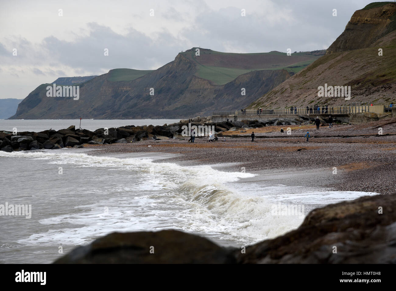 VEREINIGTES KÖNIGREICH. West Bay, Dorset, UK. 5. Februar 2017. Großbritannien Wetter. Im Anschluss an die jüngsten stürmischer See Besucher zu Fuß auf den Weststrand mit den berühmten Jurrassic im Hintergrund auf einem windigen Küste und grauen Sonntag Nachmittag. Bildnachweis: John Gurd Medien/Alamy Live-Nachrichten Stockfoto