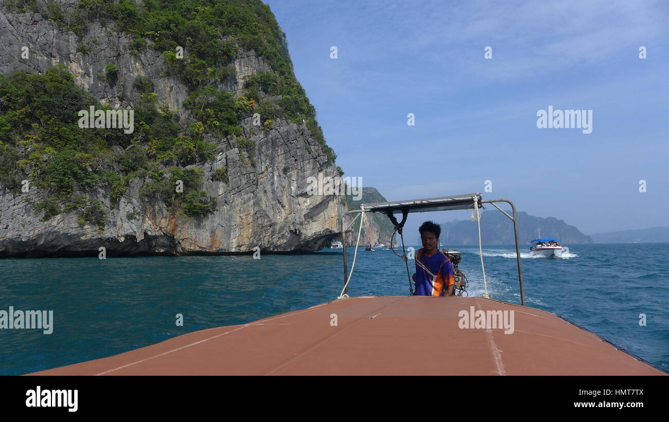 Thai Bootsmann Navigation seine Logtail Boot um spektakuläre Klippen von Koh Phi Phi Ley, Thailand Stockfoto