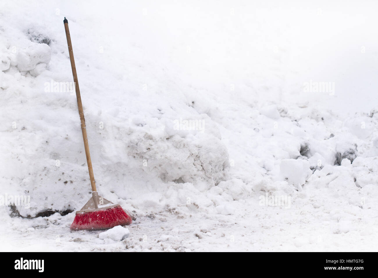 Vorderansicht des roten Hauses Besen vor Schnee gesammelt in einem Haufen im winter Stockfoto