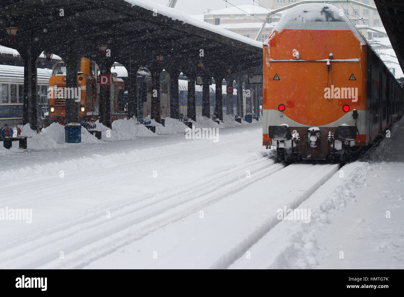 Rückansicht des Rückens eine orange Personenzug mit Schnee hielten im Bahnhof, Winter mal bedeckt Stockfoto