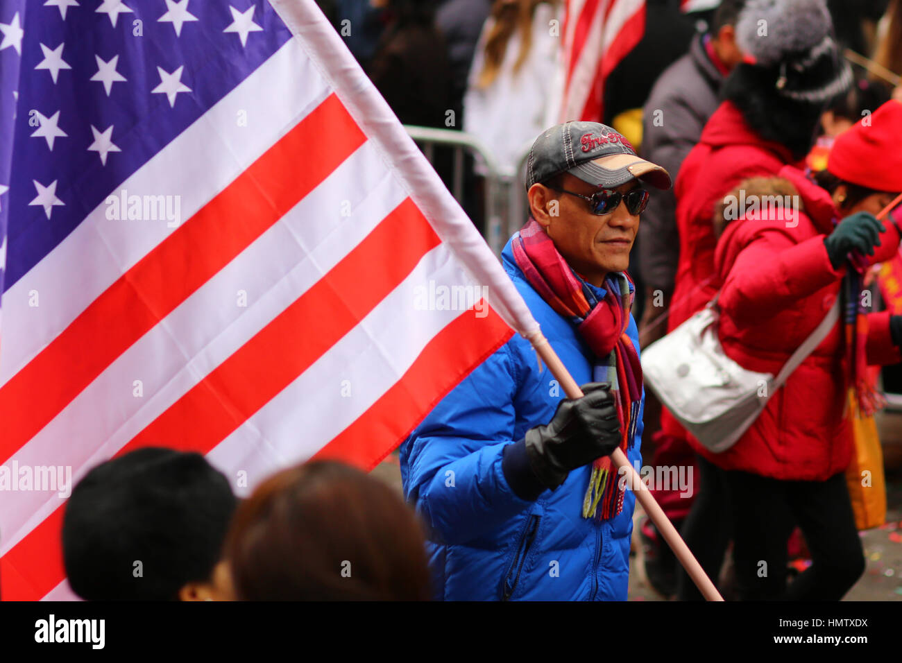 New York, USA. Februar 2017. Ein chinesischer Amerikaner trägt die amerikanische Flagge bei der Chinesischen Neujahrsparade in Manhattan Chinatown. Stockfoto