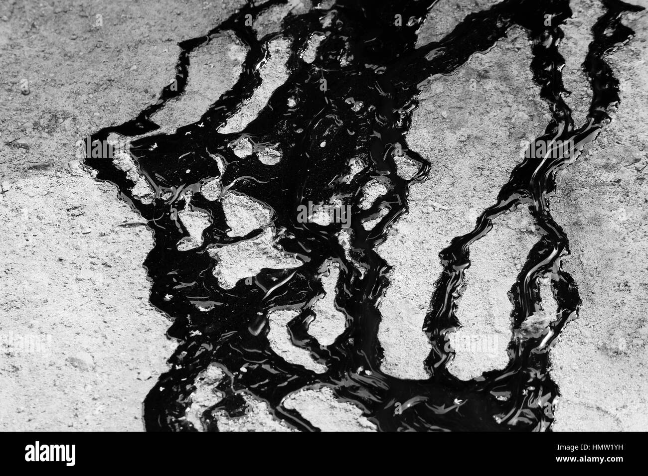 Spuren von schwarzer Teer sind auf dem Sand gegossen. Stockfoto