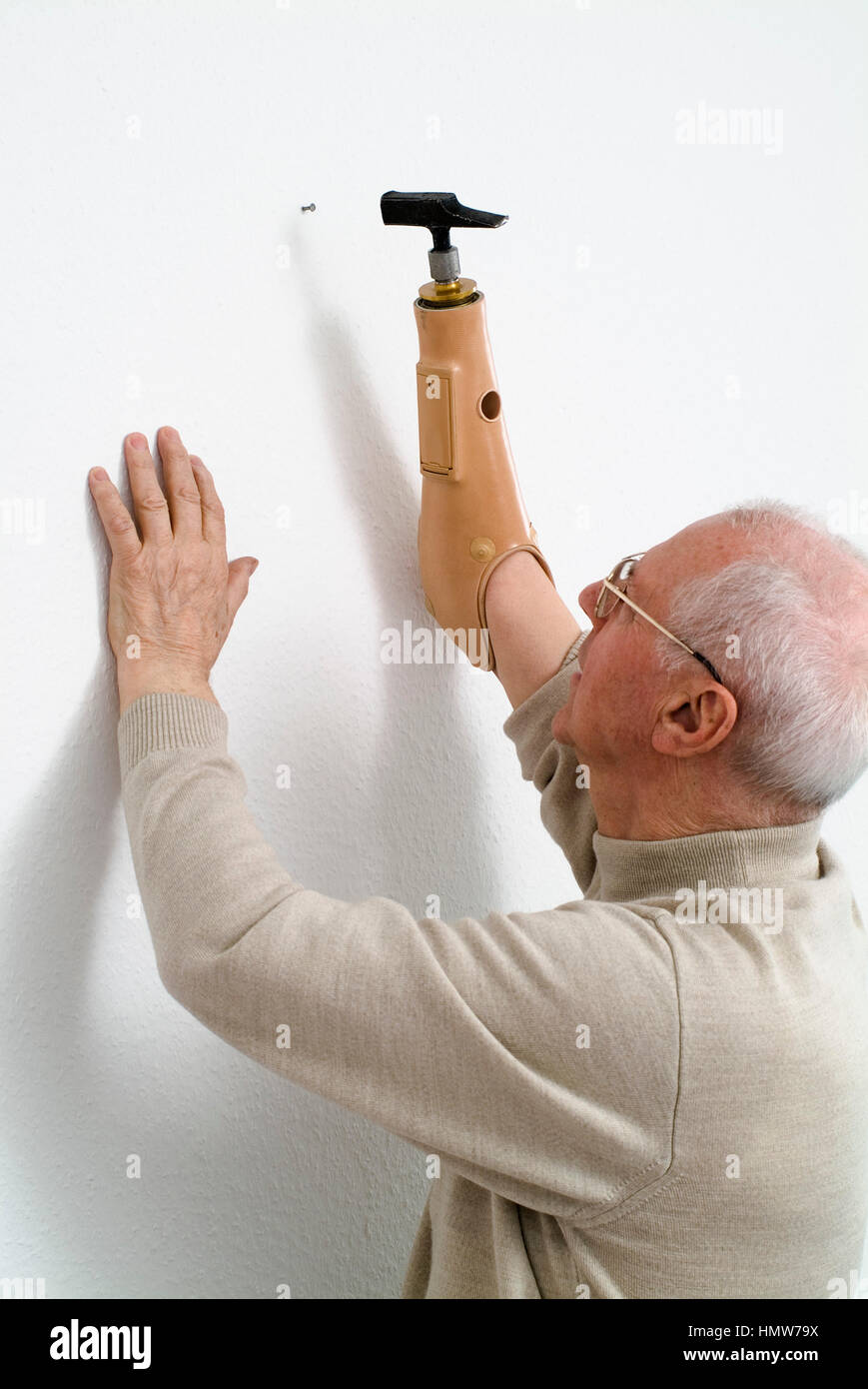 Disabled Veteran mit prothetischen myoelectric arm, unterarm Prothese, Nagel Nagel in die Wand mit einem Hammer, Deutschland Stockfoto