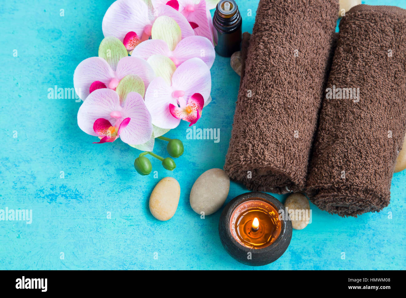 Wellness set mit Orchidee Blume, Handtücher, Kerze und Massage Stones auf Holz gemalten Hintergrund Stockfoto