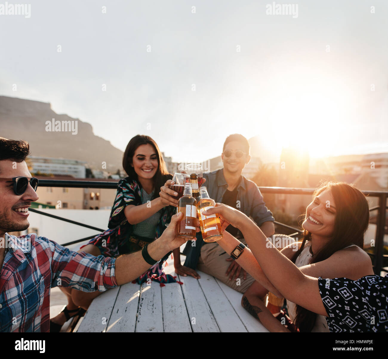 Jungen Freunden rumhängen und Drinks auf der Dachterrasse genießen. Junge Leute auf Party Toasten Biere. Stockfoto