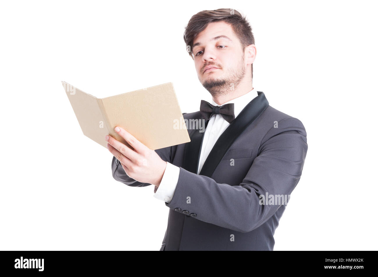 Hübscher Mann mit Smoking und Fliege Blick auf elegante Katalog oder Agenda isoliert auf weißem Hintergrund Stockfoto