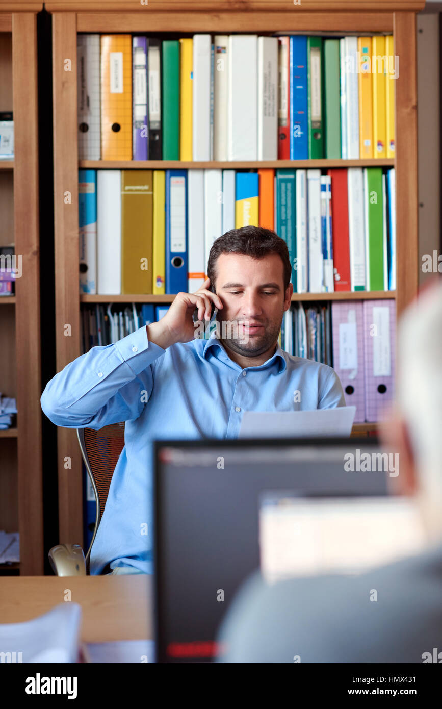 Unternehmer diskutieren Dokumente über das Telefon im Büro Stockfoto