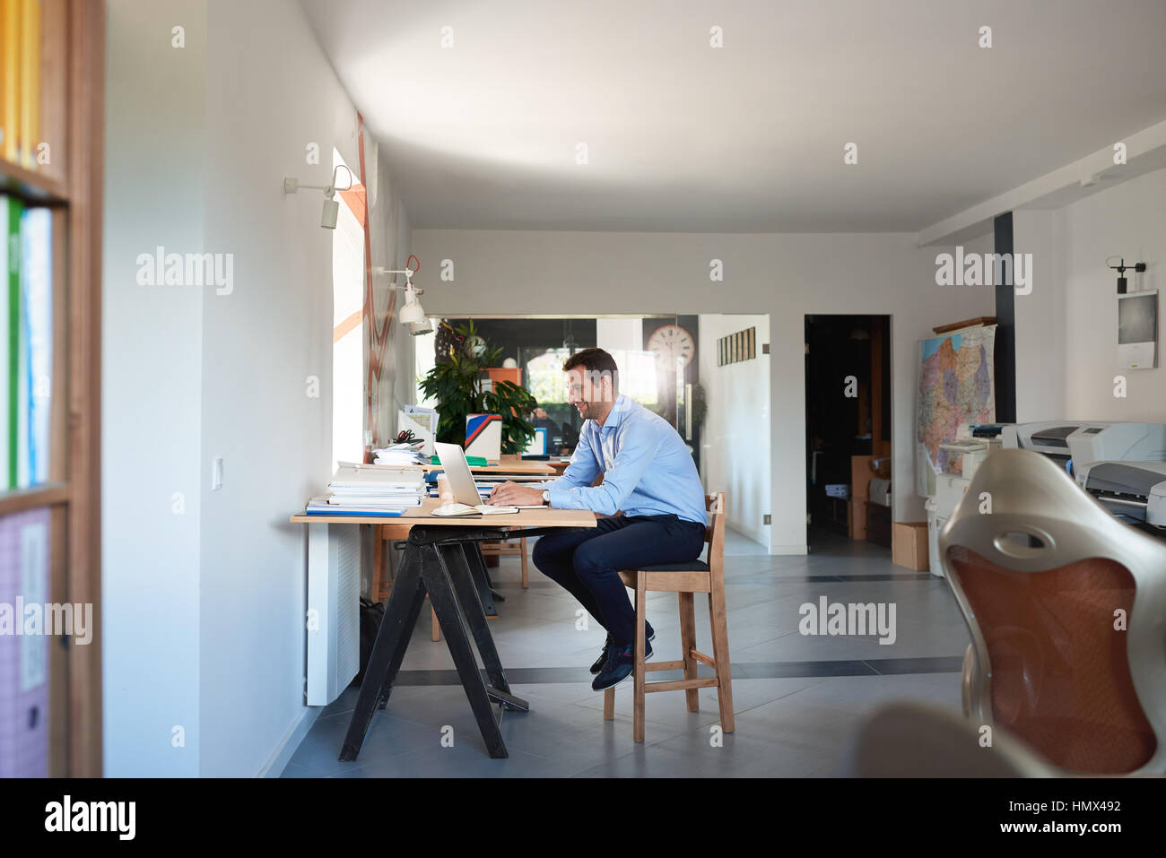 Lächelnde Geschäftsmann bei der Arbeit am Laptop in einem Büro Stockfoto