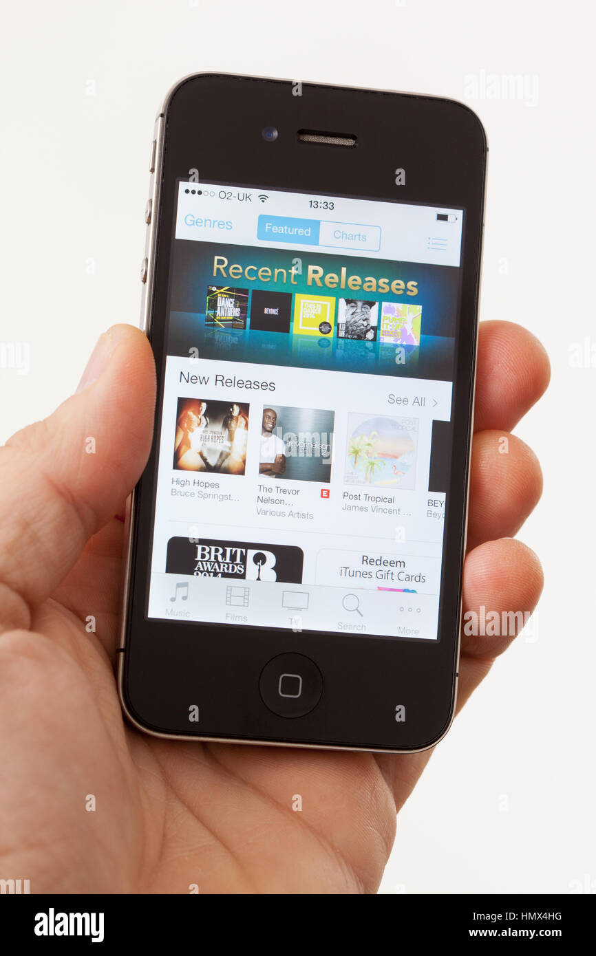 BATH, Großbritannien - 15. Januar 2014: Die Hand eines Mannes mit einem Apple iPhone 4 s die Titelseite des Apple iTunes Store angezeigt wird. Schuss in close-up ag Stockfoto