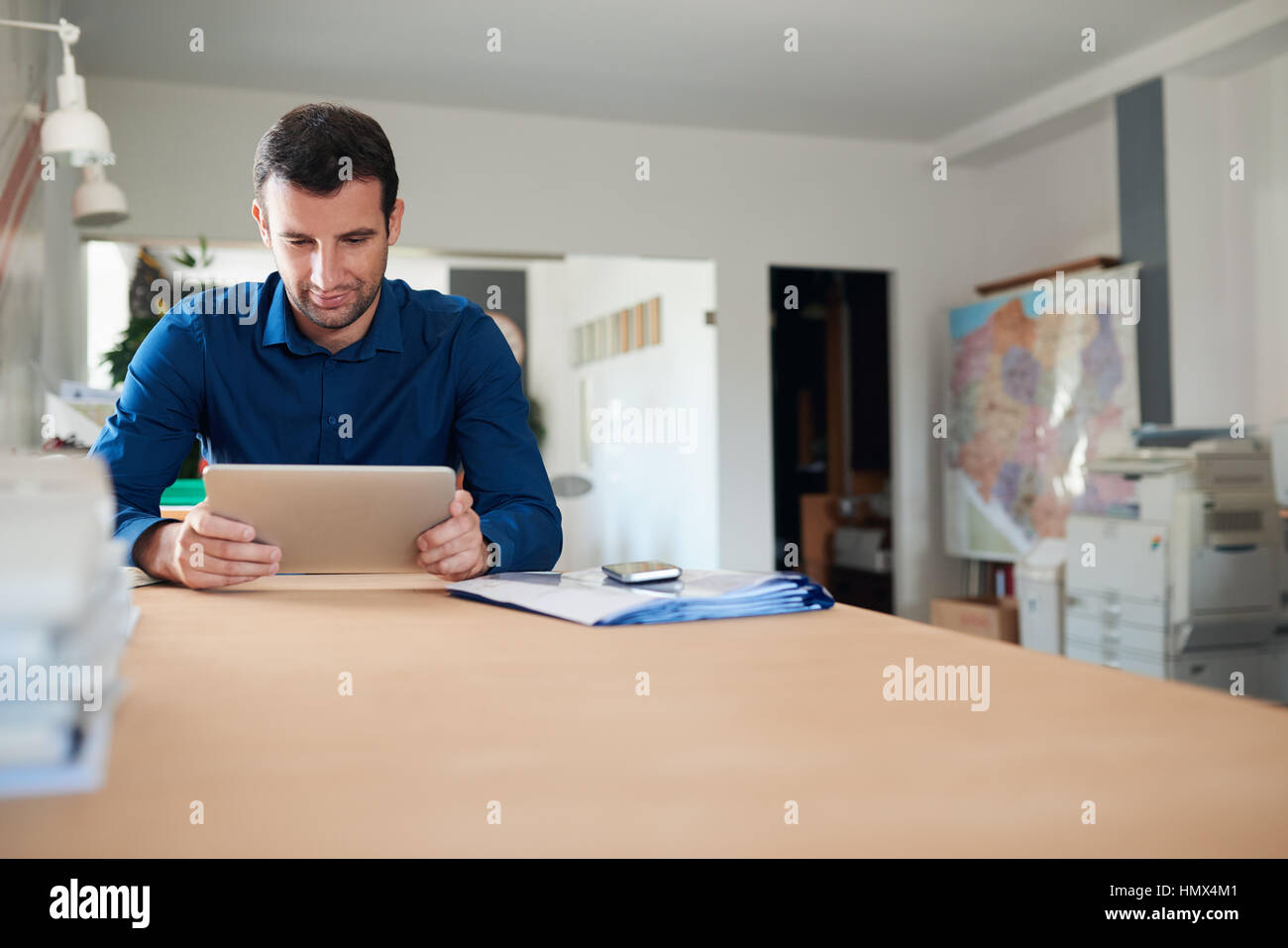 Erfolgreicher Geschäftsmann am Arbeitsplatz auf digitalen Tablet in einem Büro Stockfoto