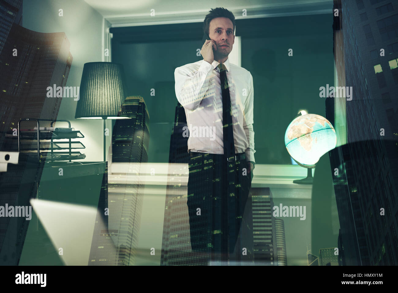 Ernste Angelegenheit Mann am Telefon im Büro mit Stadt im Hintergrund, Überstunden in der Nacht Stockfoto