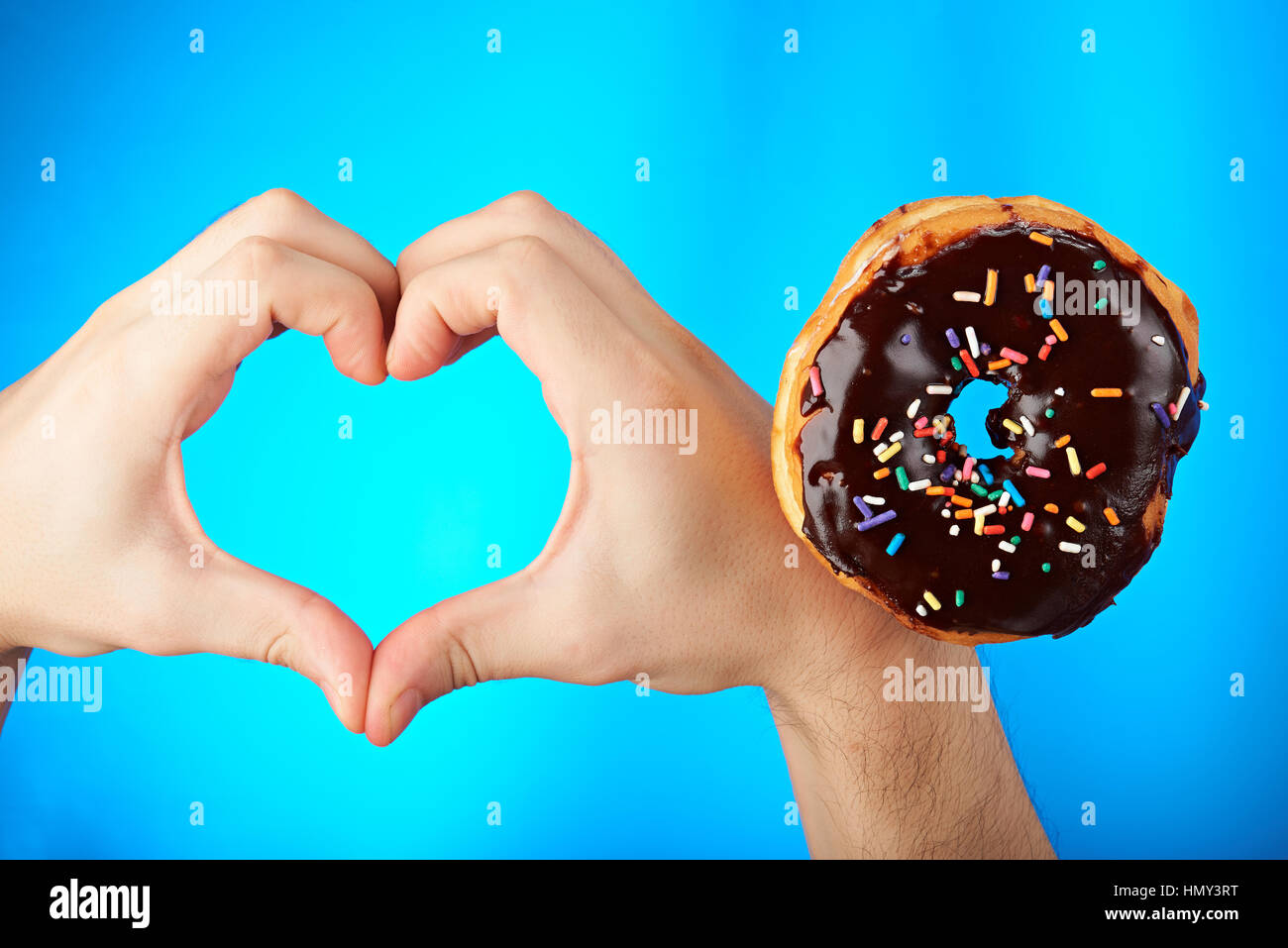 Herzform aus Händen für Donuts isoliert auf blau Stockfoto