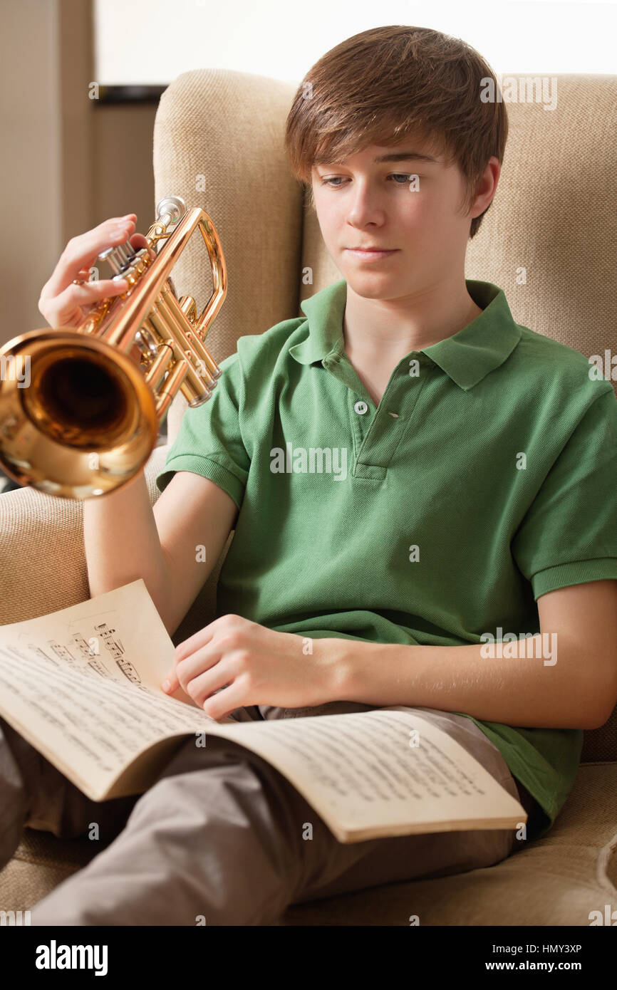 Foto von einem Teenager männlich Noten lesen und üben zu Hause seine Trompete. Stockfoto