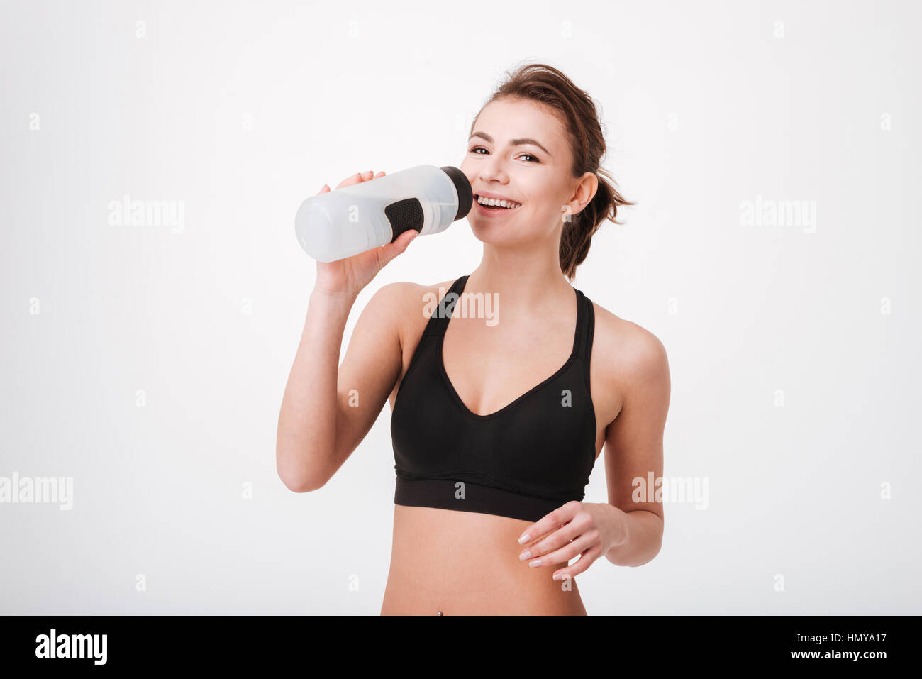Sportliche junge Frau Trinkwasser nach Training isoliert auf weißem Hintergrund Stockfoto