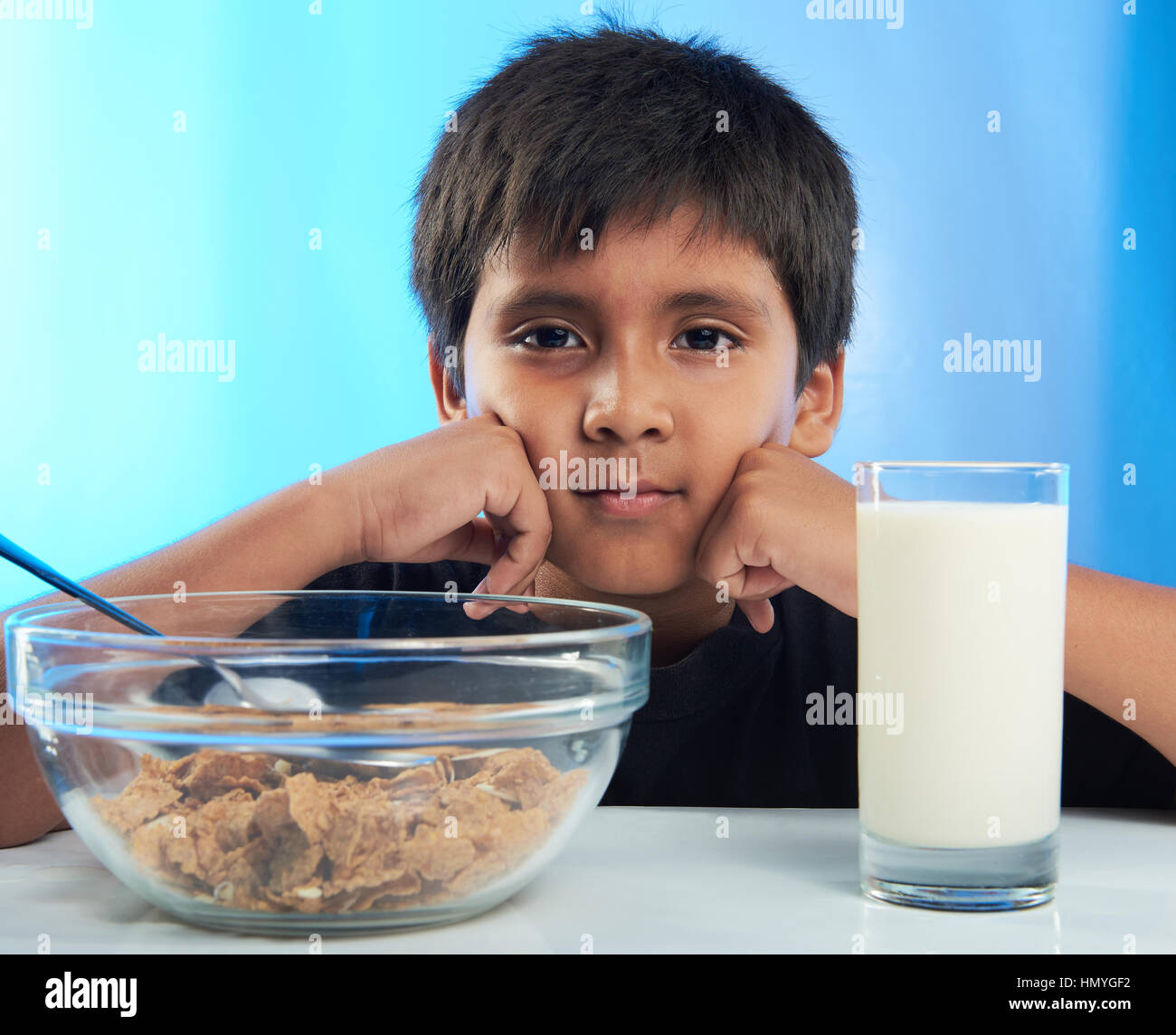 auf Tisch sitzen gelangweilt Boy am Frühstück mit Milch und Getreide Stockfoto