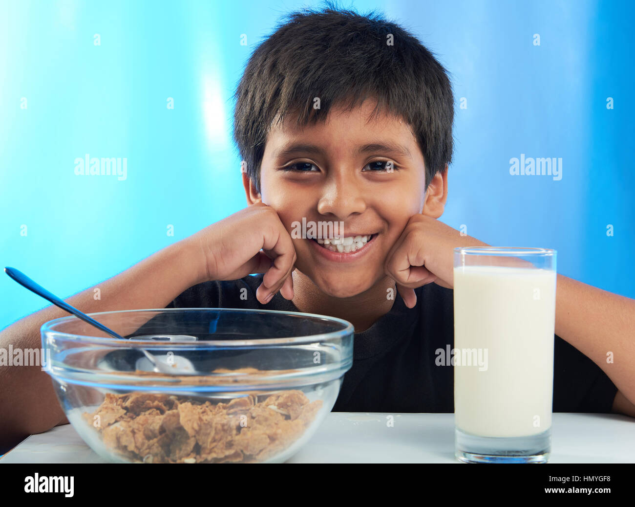 lächelnde junge auf Frühstück mit Milch und Getreide isoliert auf blau Stockfoto