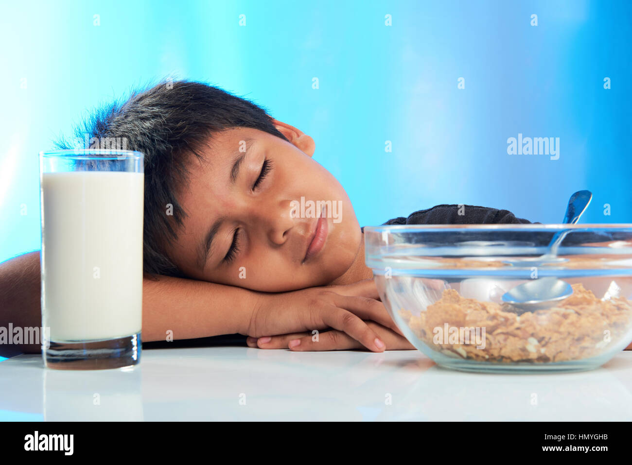 junge Schlaf am Frühstückstisch isoliert auf blau Stockfoto