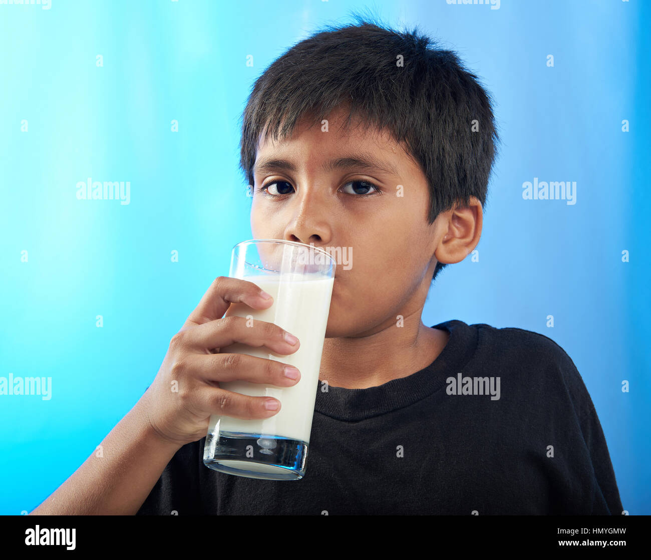 Latino Boy trinken Milch isoliert auf blau Stockfoto