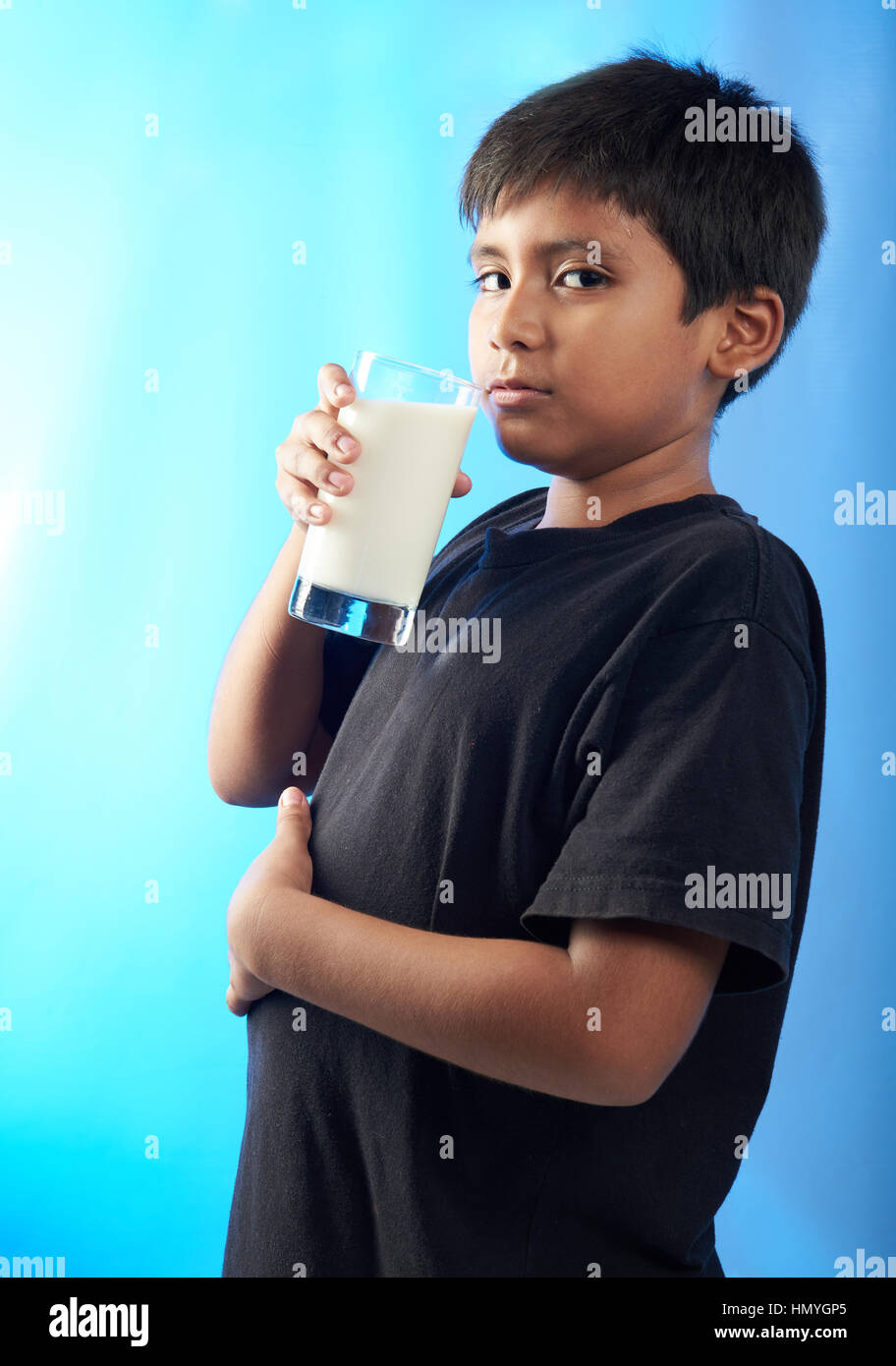 mollig Latino Boy trinken Milch isoliert auf blau Stockfoto