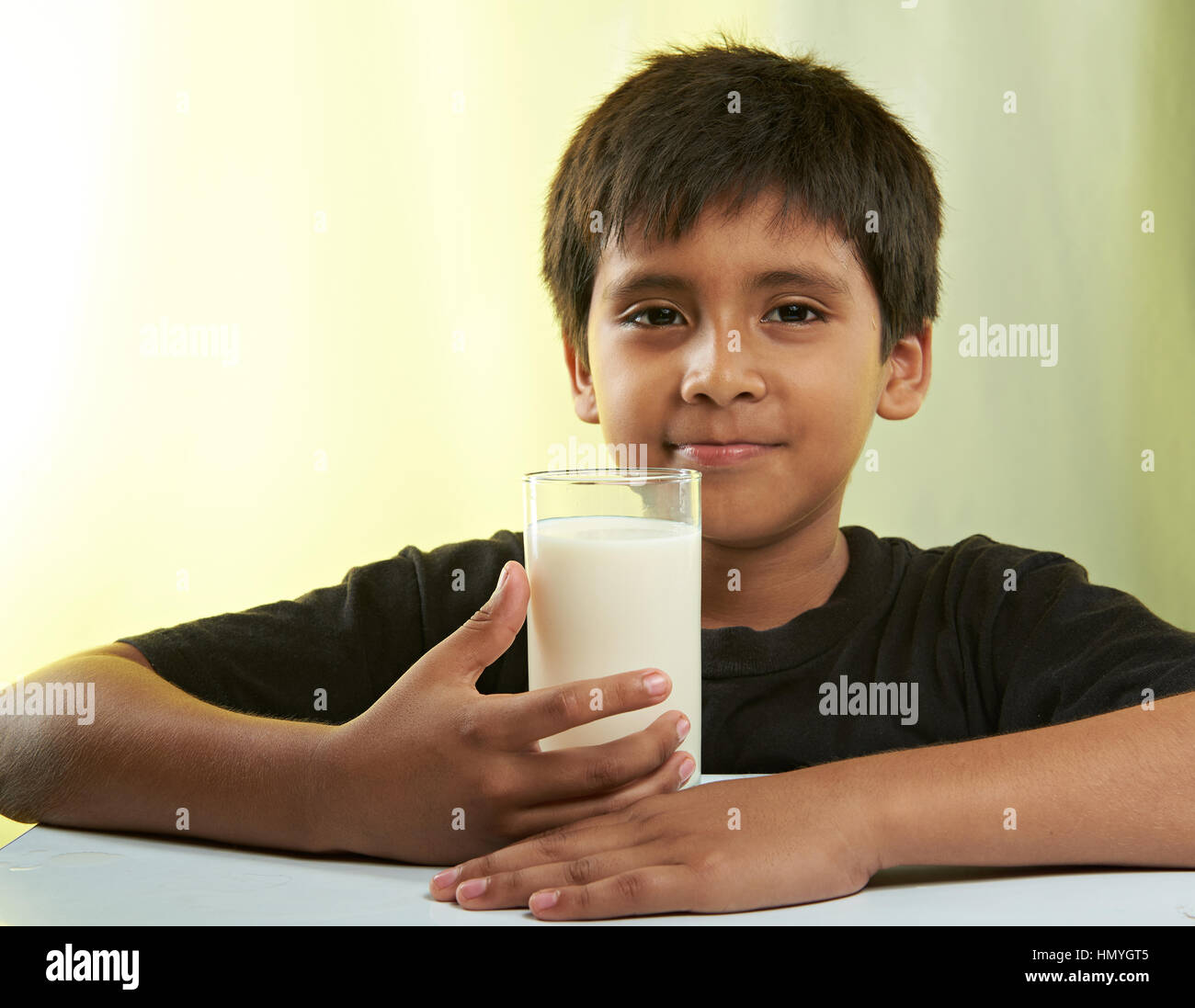 Latino Boy mit Glas Milch isoliert auf gelb Stockfoto