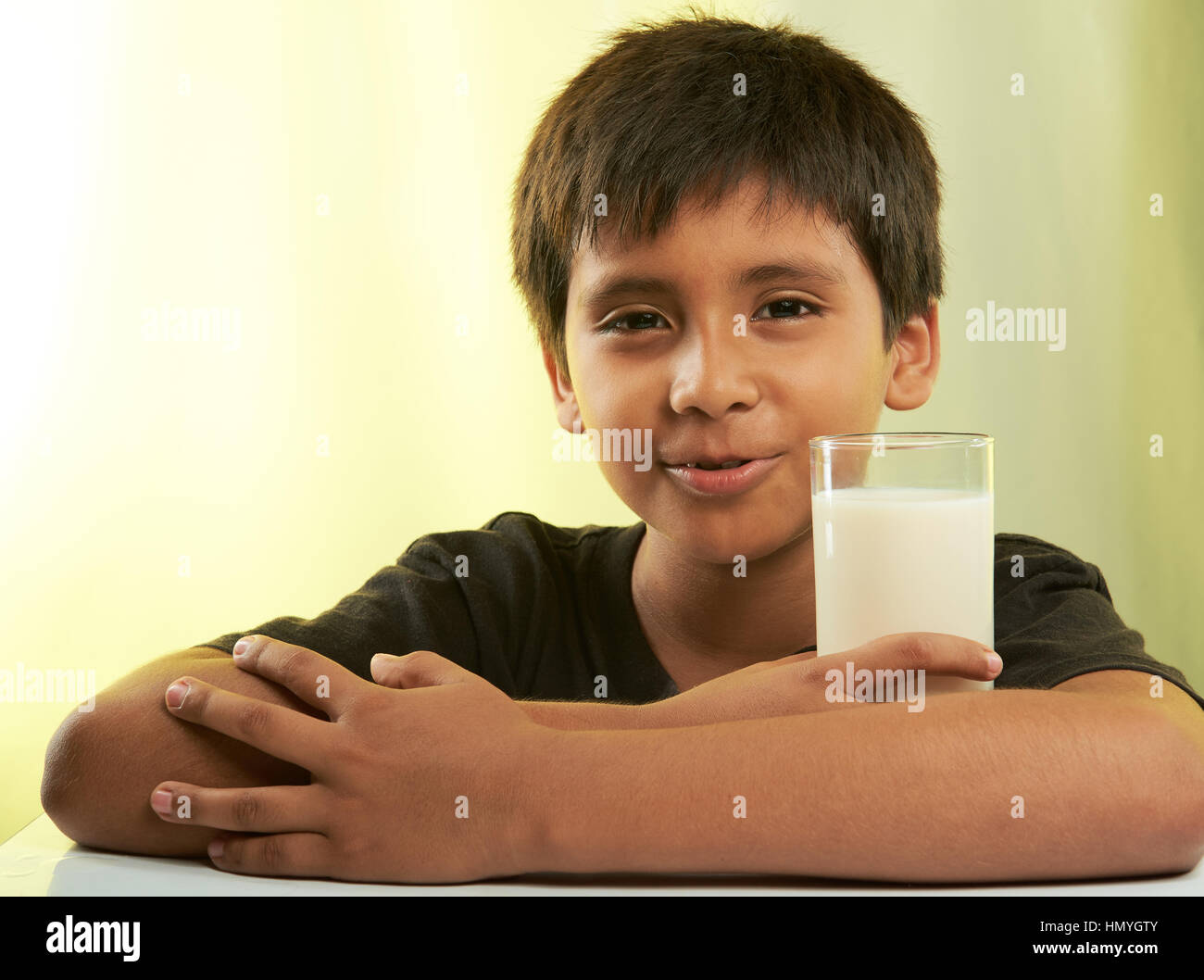 junge Halt Milch am Frühstückstisch auf gelb isoliert Stockfoto