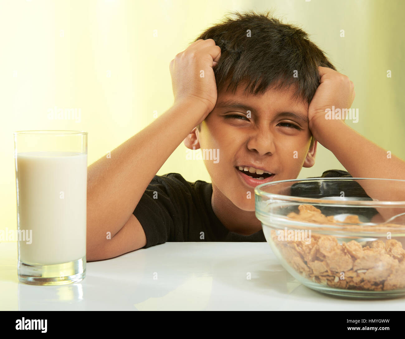 lustige junge auf Frühstück mit Milch und Getreide auf gelb isoliert Stockfoto