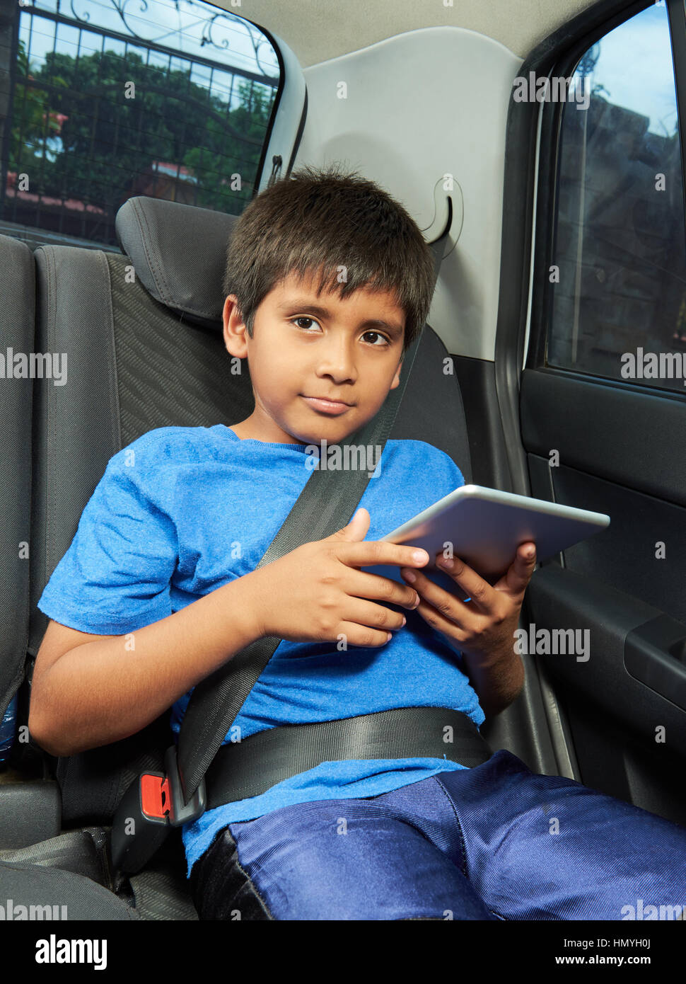Jungen spielen mit Tablet auf Rückseite Auto sitzen Stockfoto